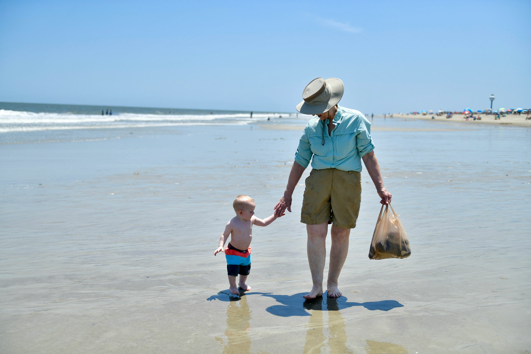 happy grandparent walking with child on the beach