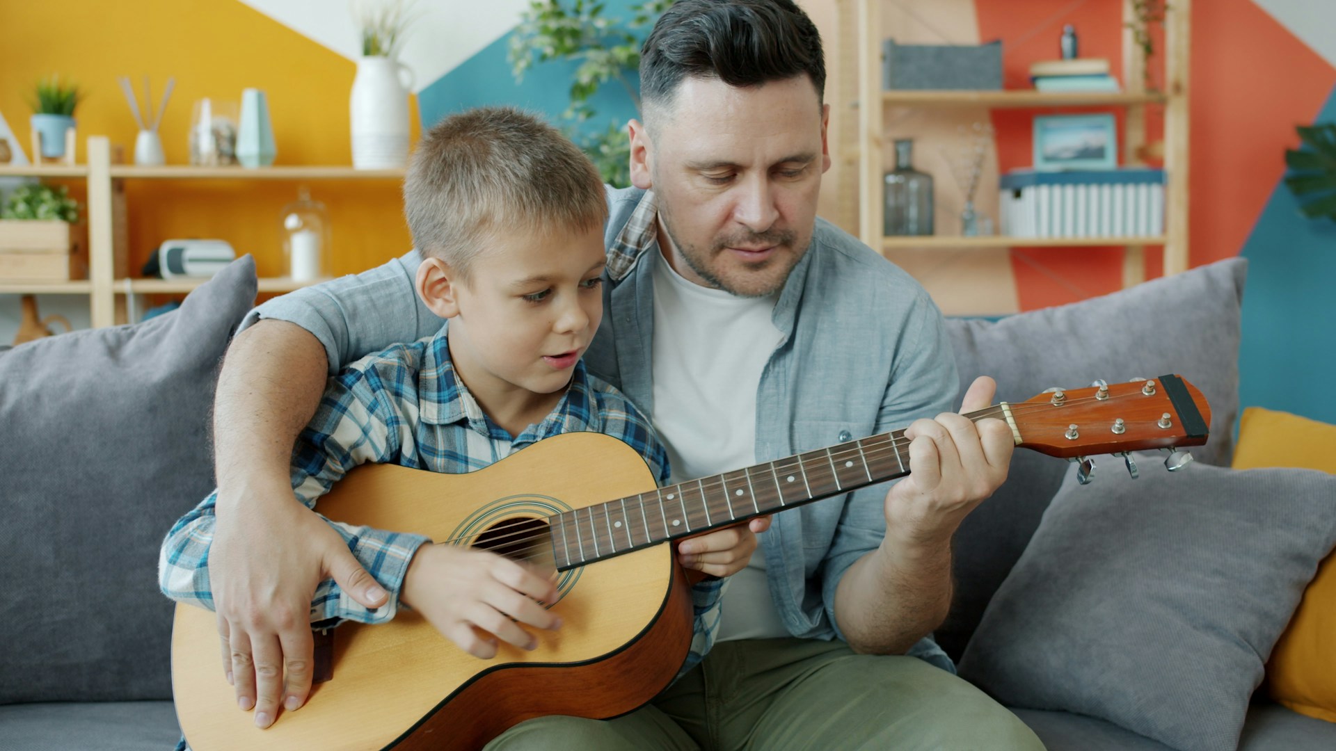 dad encouraging child to play a music instrument