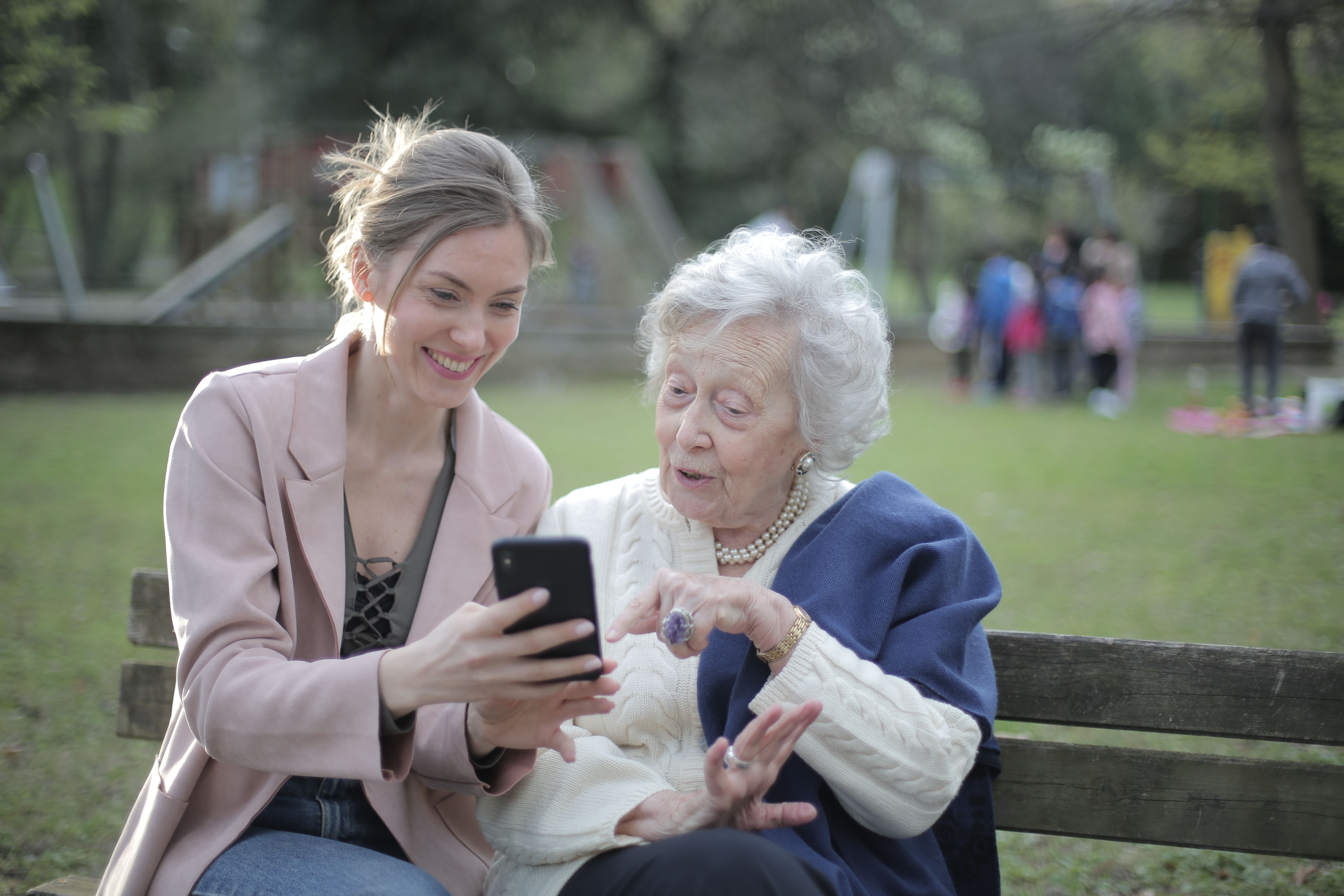 happy grandma and granddaughter looking at a phone together